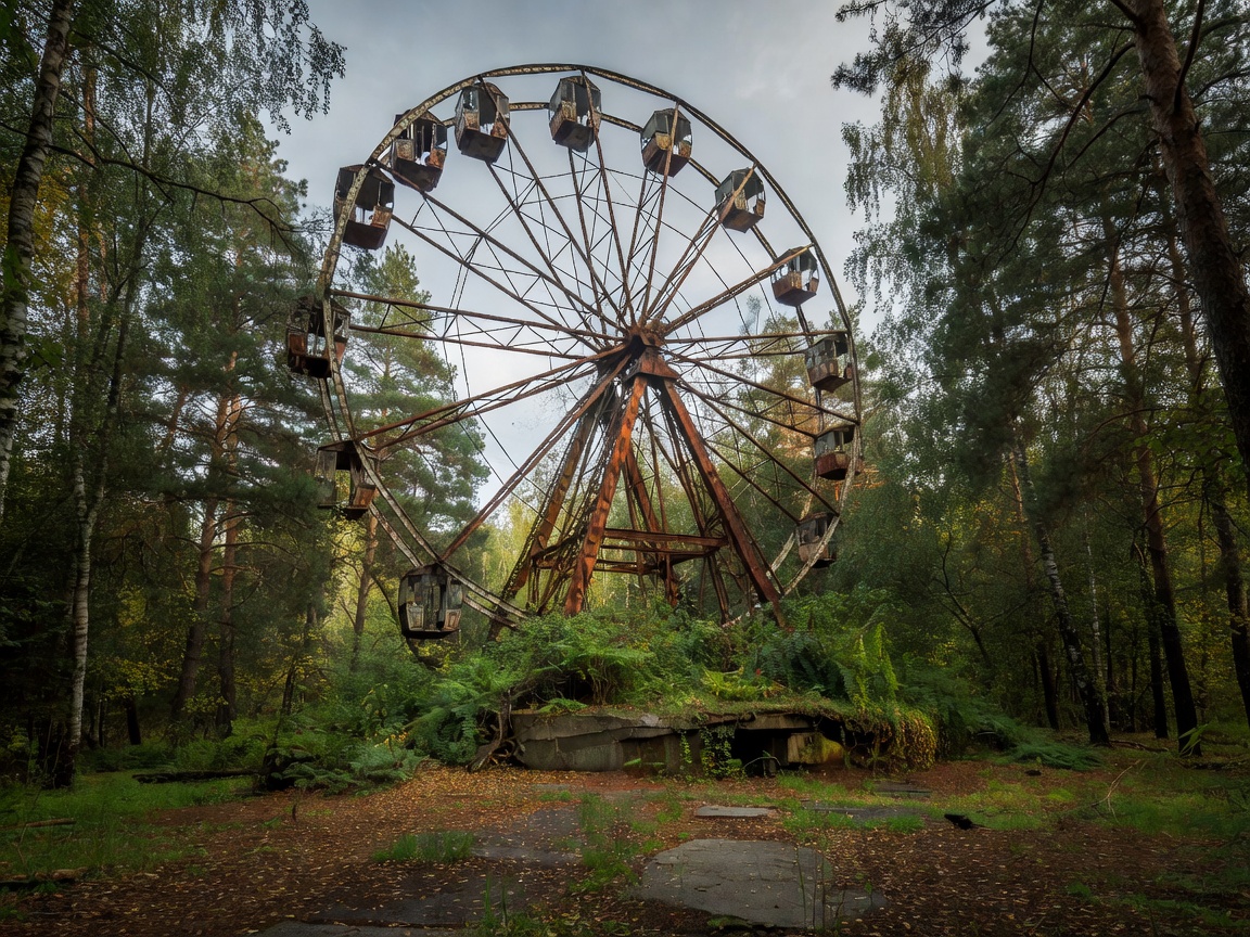 Decaying Pripyat amusement park ferris wheel standing among overgrown pine and birch forest